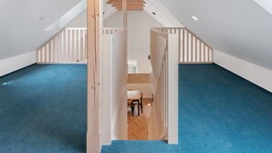 A spacious attic room with a sloped ceiling, wooden beams, and a blue carpet. - Nice apartment for 6 people with WIFI, TV, patio and pets allowed (Nový Bor)