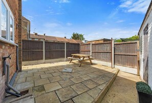 A backyard with a picnic table, a brick wall, and a wooden fence.