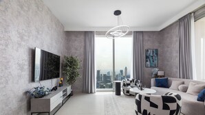 Un salon moderne doté d’un grand téléviseur, d’un canapé, d’une table basse et offrant une vue sur la ville.