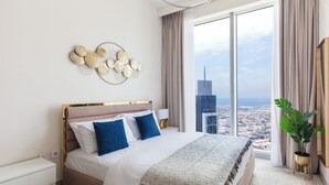 Une chambre moderne avec un grand lit, une vue sur la ville, un élément décoratif mural et une plante en pot.