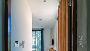 Een moderne hal met een houten deur, een zithoek en uitzicht op een balkon.