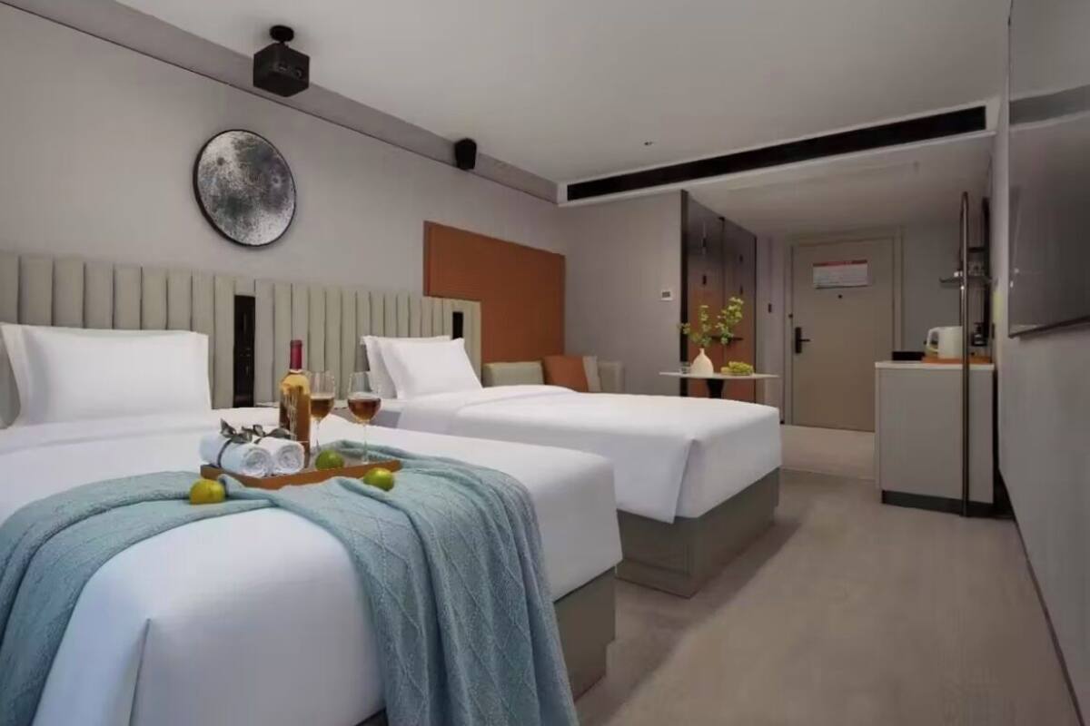 A hotel room with two beds, a minibar, a refrigerator, and a small kitchenette.