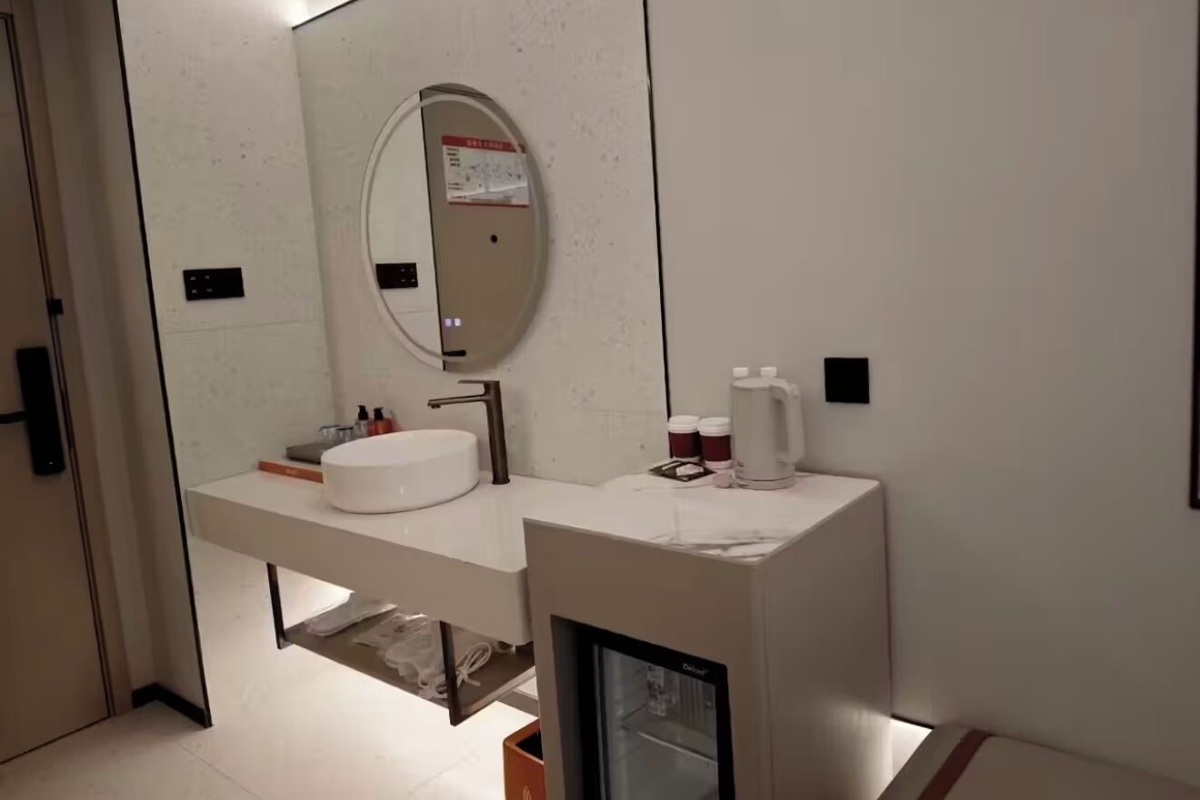 A modern bathroom with a white vanity, a large mirror, and a built-in shower enclosure.