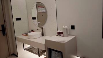 A modern bathroom with a white vanity, a large mirror, and a built-in shower enclosure.