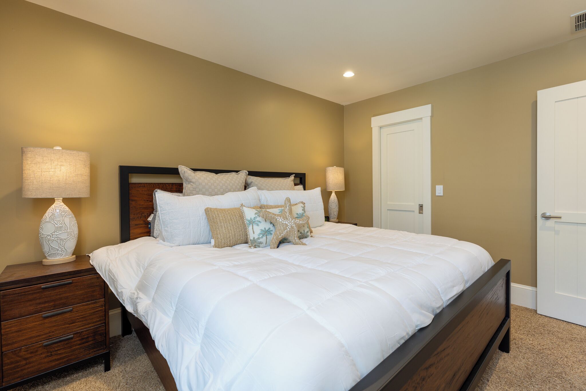 A bedroom with a large bed, two bedside tables, and a door.