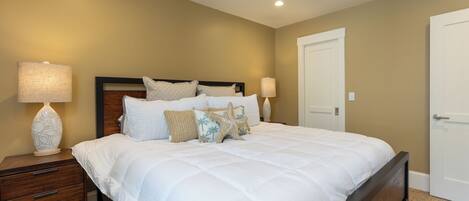 A bedroom with a large bed, two bedside tables, and a door.