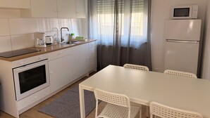 Une cuisine compacte avec un coin repas, comprenant une cuisinière, un évier et un réfrigérateur.