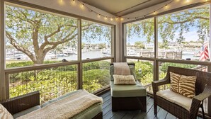 A covered outdoor seating area with wicker furniture, a view of a marina, and string lights. - Great Beach Condo in Quiet Section of Wild Dunes Resort! *301 Yacht Harbor* (Isle Of Palms)