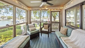 A covered outdoor seating area with wicker furniture, string lights, and a view of a marina. - Great Beach Condo in Quiet Section of Wild Dunes Resort! *301 Yacht Harbor* (Isle Of Palms)