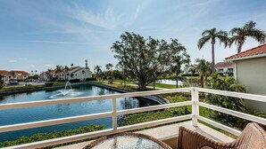Varanda com vista para uma piscina, palmeiras e edifícios residenciais.