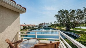 Varanda com móveis de vime, vista para uma piscina e área residencial.