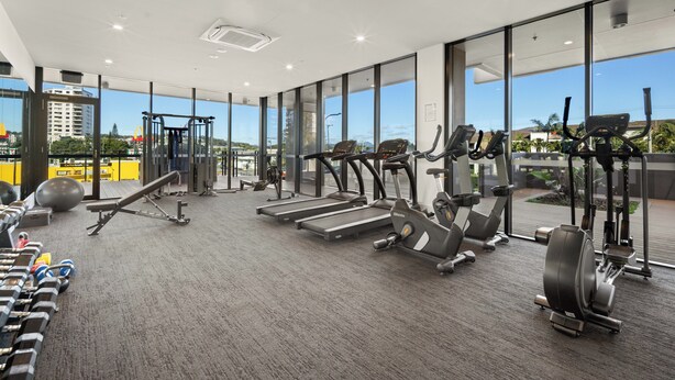 A modern gym with treadmills, elliptical machines, and free weights.