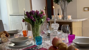 A dining table set with plates, glasses, cutlery, and a fruit basket.
