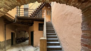 A narrow alleyway with a stone staircase leading to a building with a balcony.
