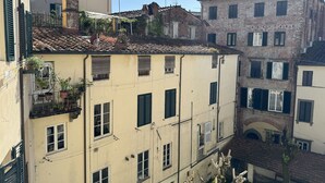 A narrow street with buildings featuring traditional architecture, including terracotta roofs and shuttered windows.