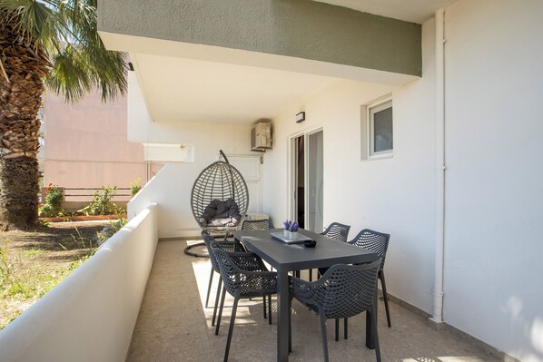 A balcony with a table and chairs, a hanging chair, and a view of the building in the background.