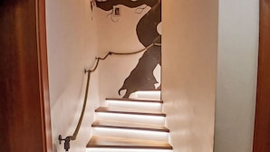 A staircase with a unique tree design on the wall, a handrail, and a light fixture. - Beautiful  villa for 7 guests with WIFI, TV and terrace (Sankt Bartlmä)