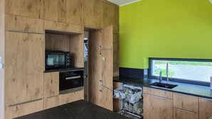 A kitchen with wooden cabinetry, a built-in microwave, oven, and dishwasher, and a window with a view. - Beautiful  villa for 7 guests with WIFI, TV and terrace (Sankt Bartlmä)