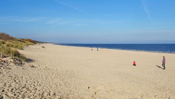 A wide sandy beach with a clear blue sky and a few people walking. - Beautiful apartment for 4 guests with WIFI, TV and terrace (Trassenheide)