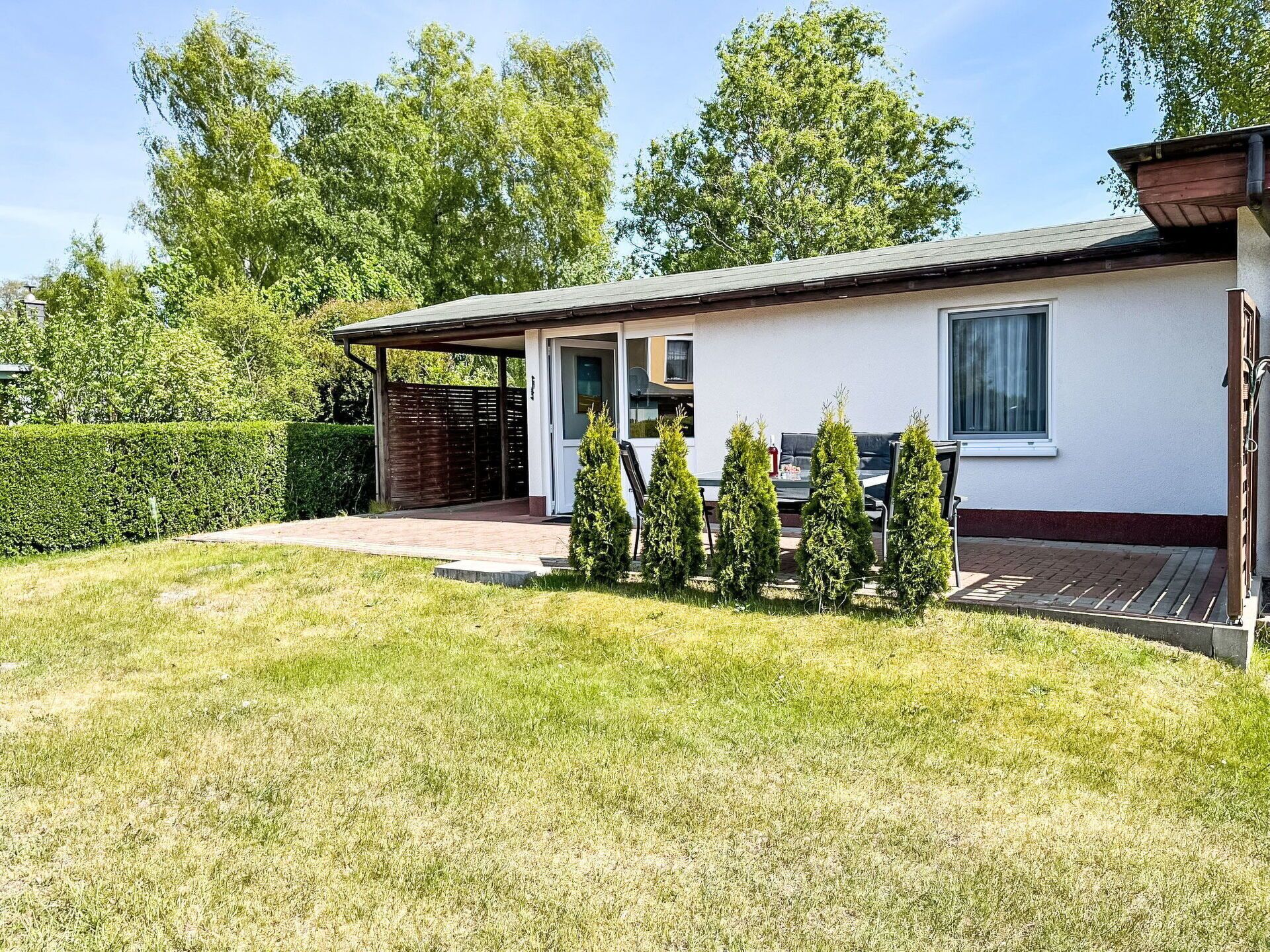 A single-story house with a covered porch, a small deck, and a well-maintained lawn.