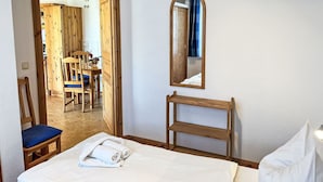 A hotel room with a bed, a wooden chair, a small wooden shelf, and a mirror on the wall. - Cosy apartment for 3 people with WIFI, TV and terrace (Trassenheide)