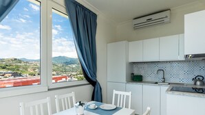 A modern kitchen with white cabinets, a window with blue curtains, and a view of a cityscape. - Cosy apartment for 6 guests with WIFI, A/C, TV, balcony and pets allowed (Sanremo)