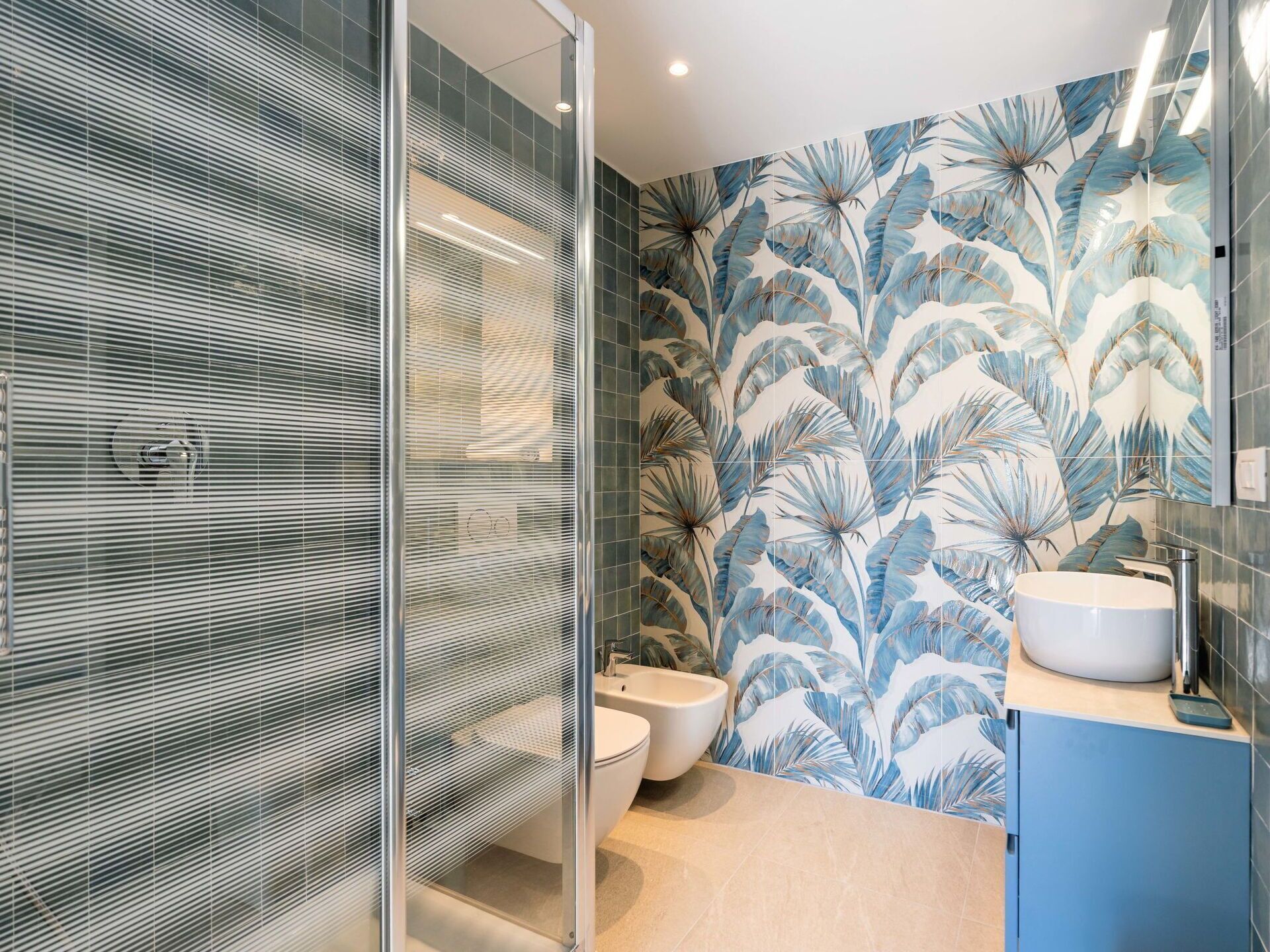 Une salle de bain moderne avec une douche à parois de verre, des toilettes et un lavabo avec un meuble bleu.
