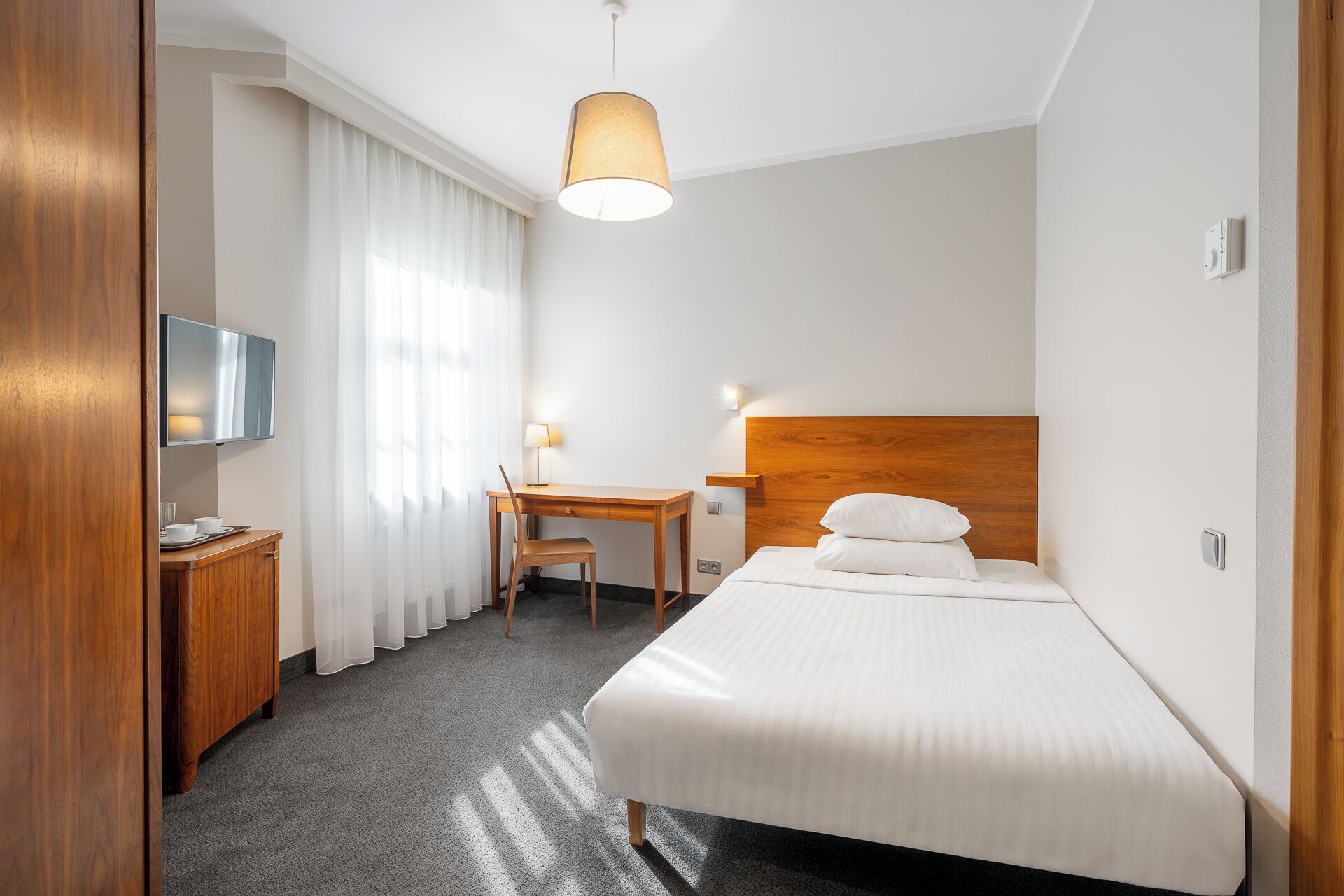 Ein Hotelzimmer mit einem Bett, einem Schreibtisch, einem Sessel, einem Fernseher und einer Lampe.