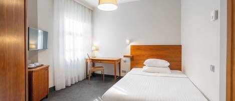 Ein Hotelzimmer mit einem Bett, einem Schreibtisch, einem Sessel, einem Fernseher und einer Lampe.
