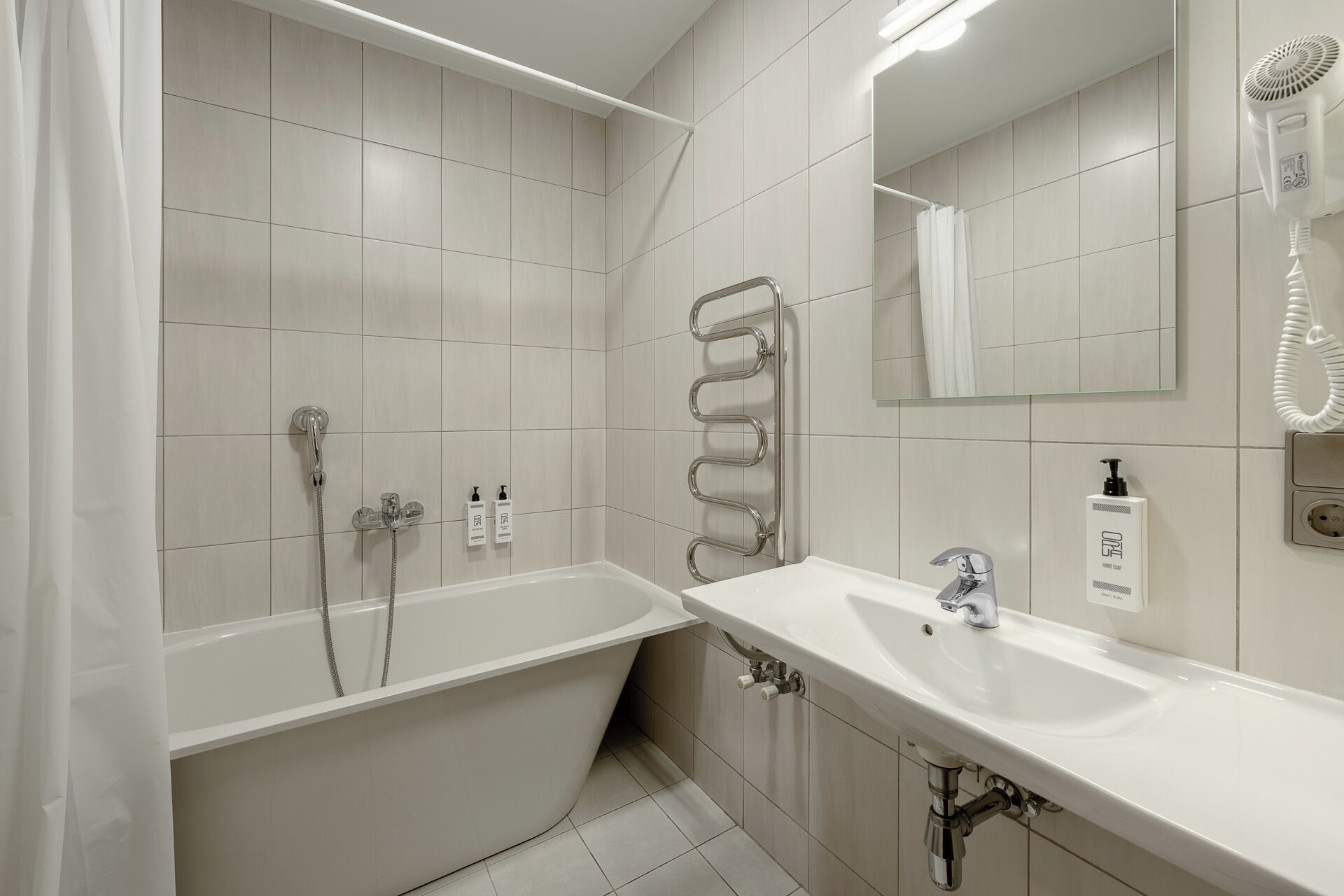 Une salle de bain moderne équipée d’une baignoire, d’un lavabo, d’une douche et d’un porte-serviettes.