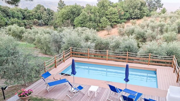 A pool with a wooden deck, blue lounge chairs, and a wooden fence. - Beautiful private villa for 9 people with private pool, WIFI, A/C, TV, patio and pets allowed (Roccastrada)
