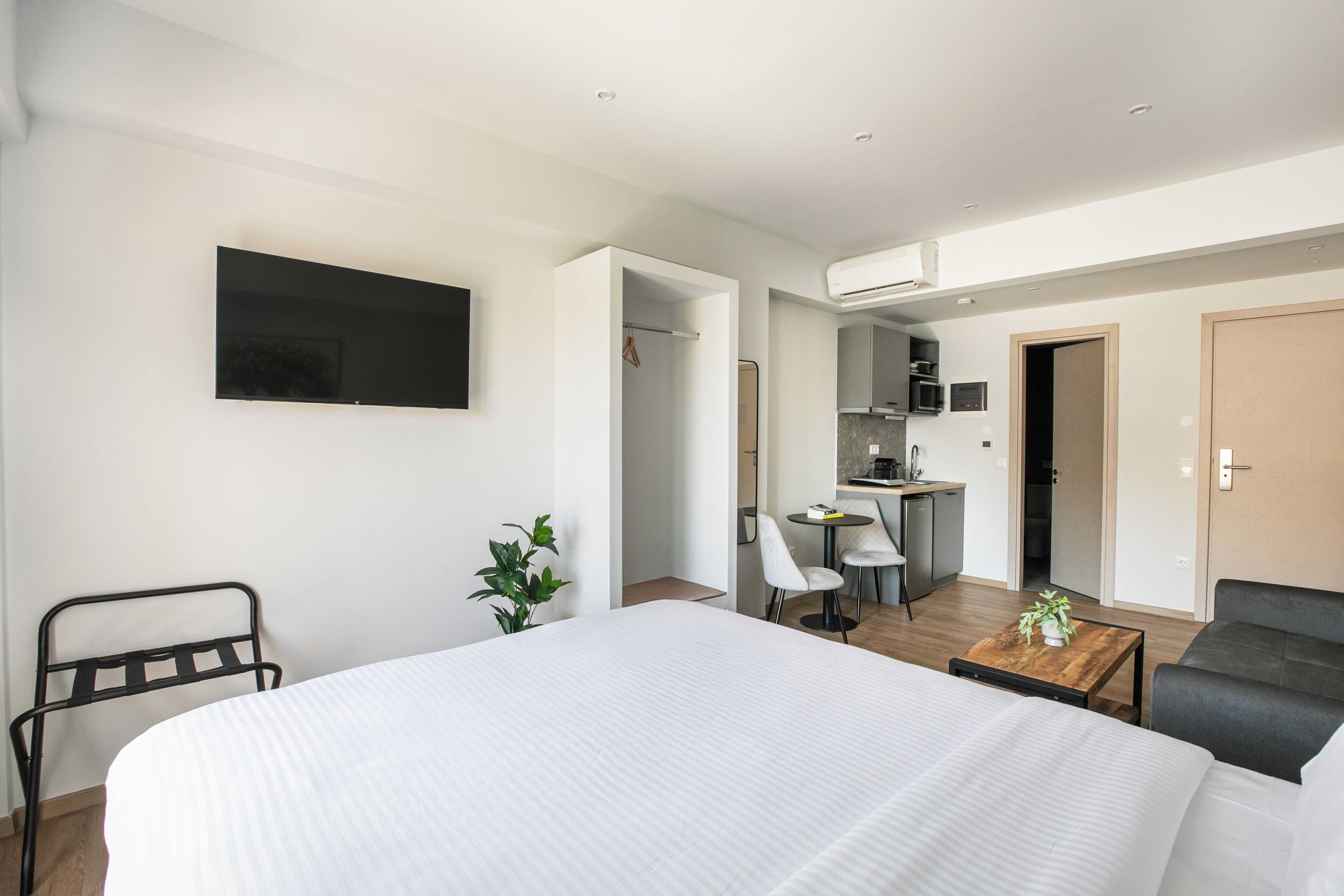 Een moderne hotelkamer met een groot bed, een bureau, een stoel, een tafeltje met een plant en een aan de muur bevestigde televisie.