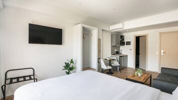 Een moderne hotelkamer met een groot bed, een bureau, een stoel, een tafeltje met een plant en een aan de muur bevestigde televisie.