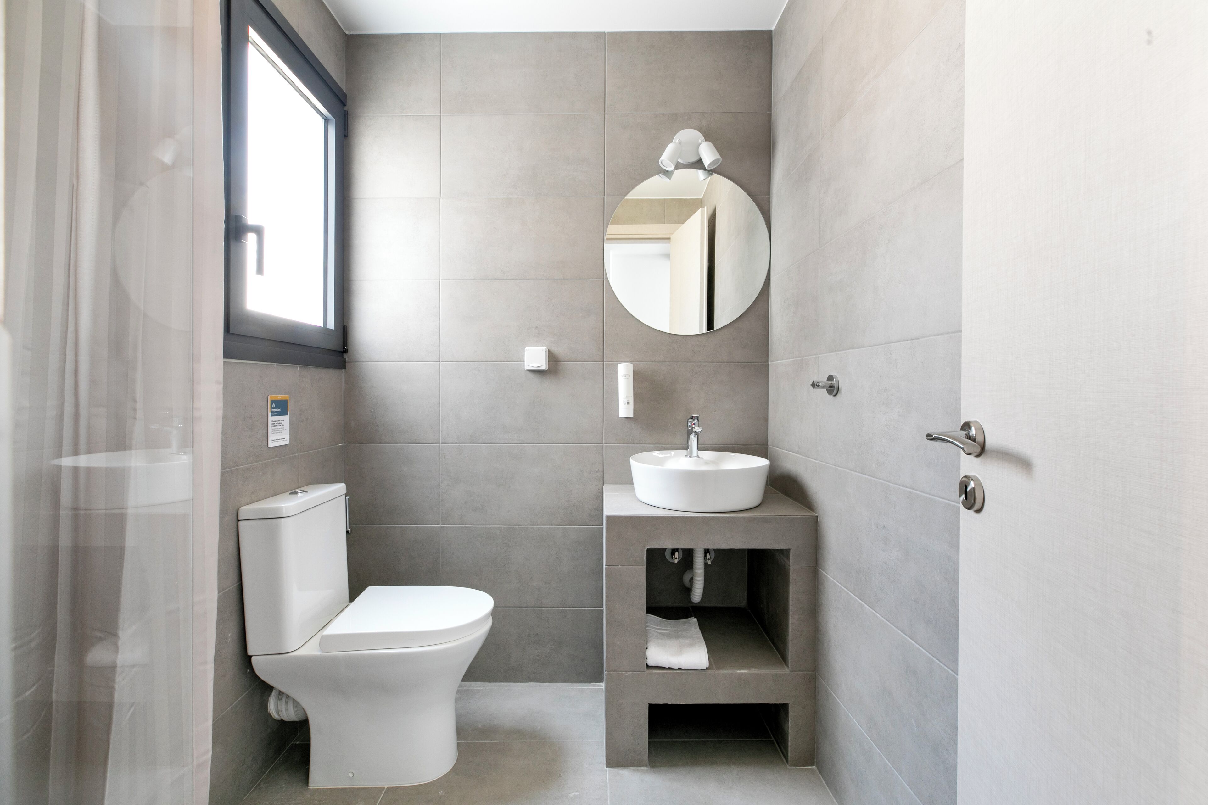 A modern bathroom with a toilet, sink, and mirror.