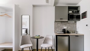 Une petite cuisine équipée d’un four à micro-ondes, d’un évier et d’un petit réfrigérateur. On y trouve une table ronde avec deux chaises et un miroir accroché au mur.