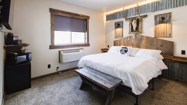Ein Schlafzimmer mit einem Bett, einer Bank, einem Heizgerät und einem an der Wand befestigten Regal mit einer Mikrowelle.