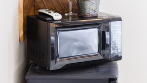 Eine Küchenzeile mit einer Keurig-Kaffeemaschine, einer Mikrowelle, einem Korb und einem Weinglas auf einem Holzboden.