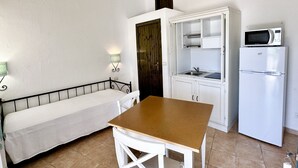 A compact kitchenette with a microwave, refrigerator, and a small dining area with a bench and table. - LE RESIDENZE ACQUA DI MARE (Eden Beach)