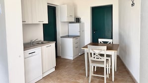A compact kitchen with white cabinets, a built-in microwave, and a dining area with a table and chairs. - LE RESIDENZE ACQUA DI MARE (Eden Beach)