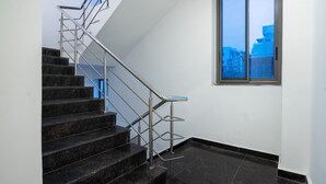 Una escalera con barandillas metálicas y un ventanal con vista a la ciudad.