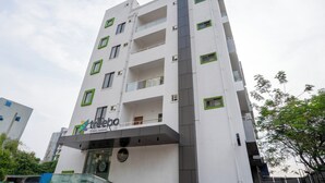 Un edificio de varios pisos con fachada blanca, marcos de ventanas verdes y un letrero que dice 'treebo Suites Mankato'.