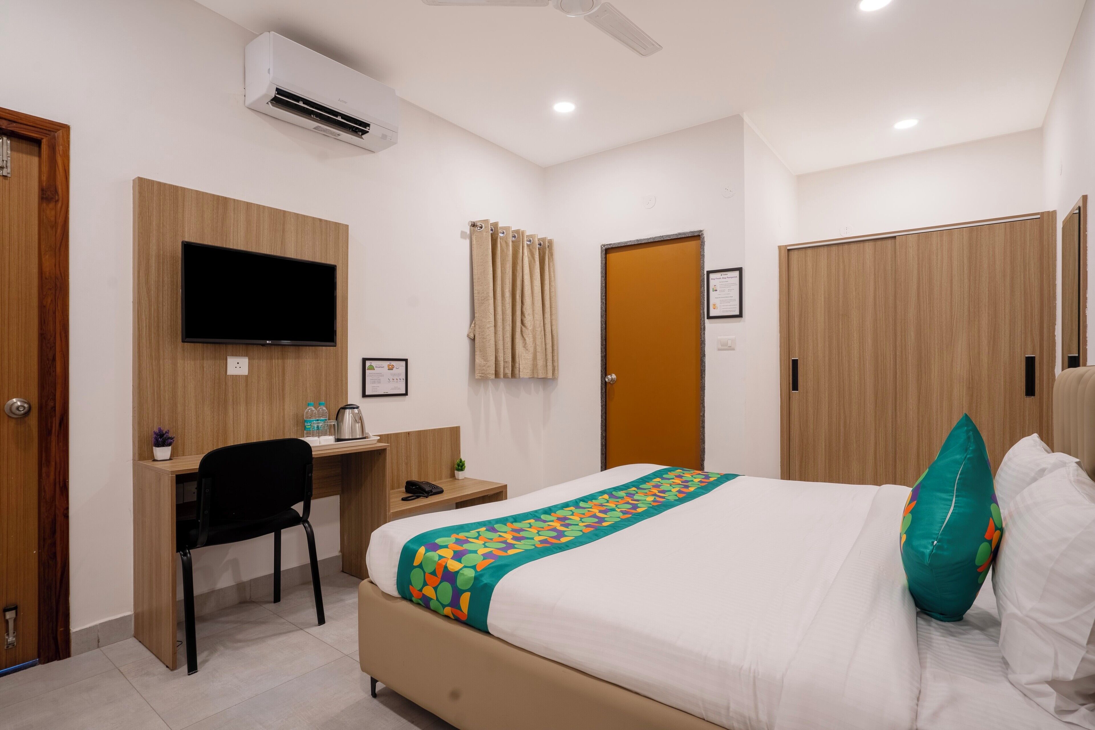 Une chambre d’hôtel comprenant un lit, un bureau, une chaise, une télévision et une armoire.
