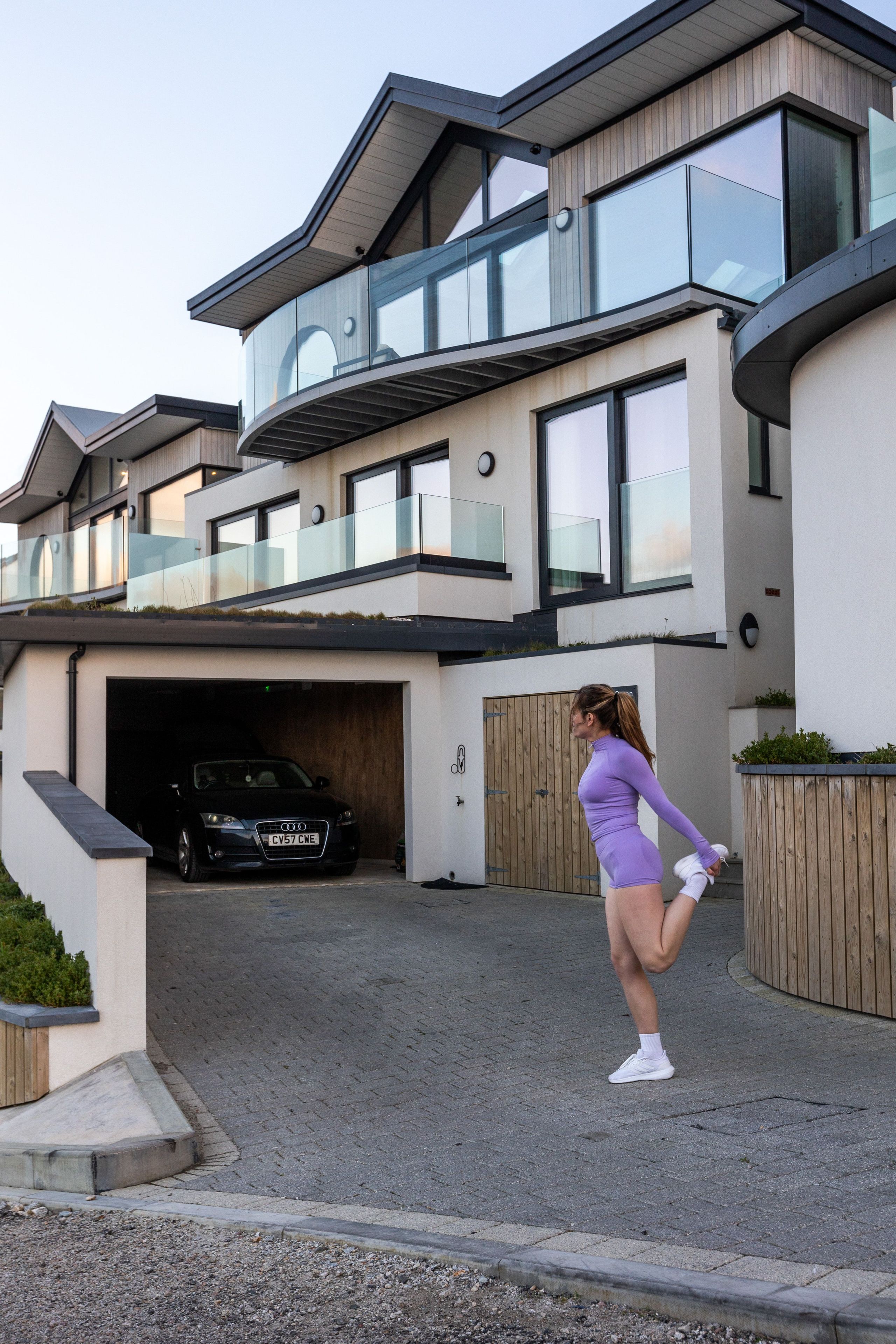 A modern two-story house with a garage, a balcony, and a driveway.