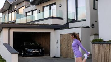 A modern two-story house with a garage, a balcony, and a driveway.
