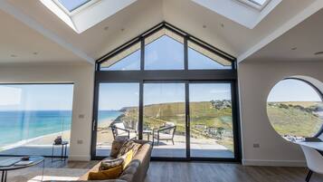 A spacious room with a large glass wall offering a view of the beach and ocean.