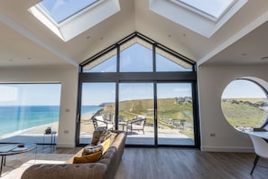 A spacious room with a large glass wall offering a view of the beach and ocean.