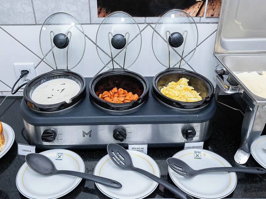 A buffet setup with three food stations labeled "CANJICA," "MOLHO DE LEICHA," and "OVOS MEXIDOS."