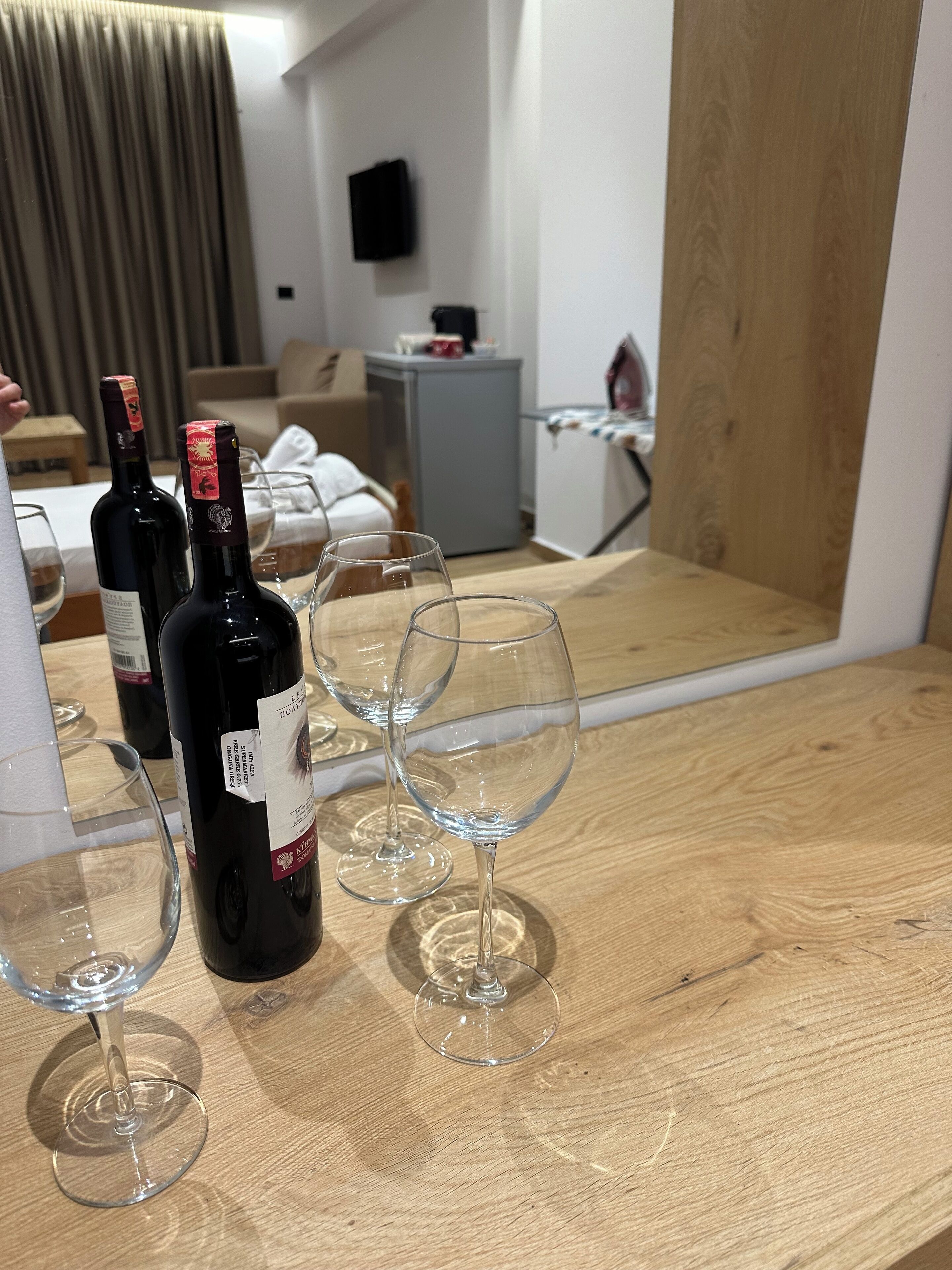 A room with a wooden table holding wine bottles and glasses.