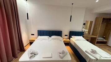 A hotel room with two beds, a wooden wardrobe, and a mirror.