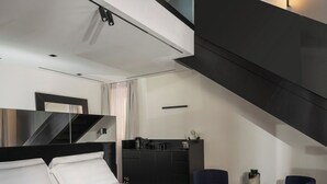 Un dormitorio moderno con una cama grande, un escritorio, dos sillas y una escalera.